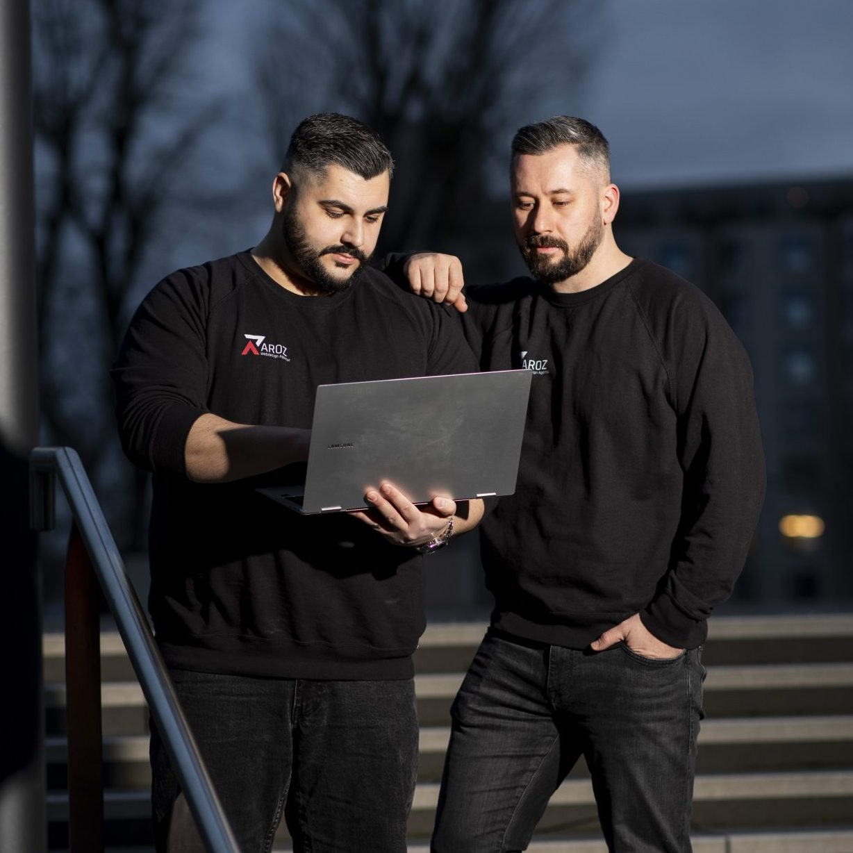 Startseite 2 Das Bild zeigt die beiden Gründer Adem Zora und Renato Mamaj, wie sie am Laptop arbeiten. Die Szene steht sinnbildlich für die Konzentration und Zusammenarbeit bei der Entwicklung einer digitalen Präsenz. Durch ihre gemeinsame Arbeit am Laptop demonstrieren sie ihr Engagement für die Webpräsenzgestaltung ihres Unternehmens. Diese authentische Momentaufnahme vermittelt den Wert von Teamarbeit und persönlichem Engagement bei der Gestaltung einer erfolgreichen Online-Präsenz.
